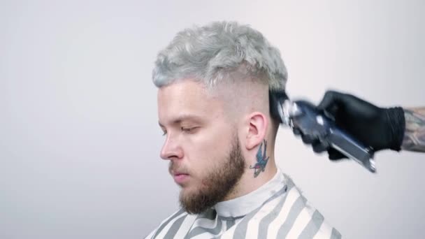 Coupe de cheveux dans le salon de coiffure avec un rasoir électrique. Portrait d'un blond — Video