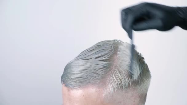 Чоловік зачісується ножицями світлого волосся на білому тлі — стокове відео