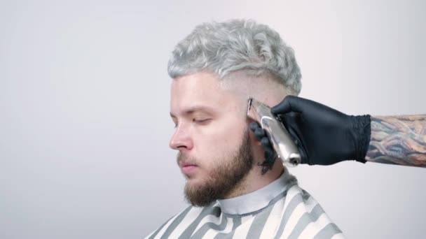 Fodrász, fodrászat, egy elektromos borotva. Egy szőke férfi portréja — Stock videók