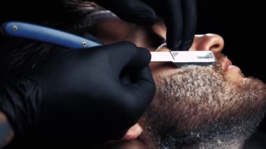 Ellerinde siyah eldiven bir adamın yüzünü tıraş yakın çekim