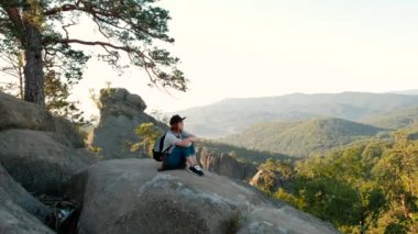 Hayat güzel manzara düşünmeye bakarak dağın tepesinde oturan genç bir kadın. Bir kızla tatile gidiyor.