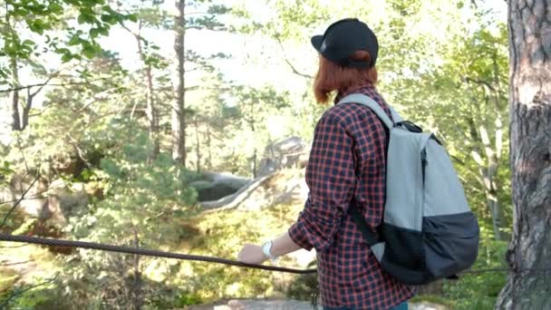 Wanderer mit Rucksack auf dem Gipfel eines Berges mit Sonnenstrahlen. junge Frau gesunde aktive Lebensweise. Abenteuer in der Natur. 4k — Stockvideo