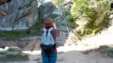 Ağır çekim portre kız seyahati ile smartphone kullanarak uçurumdan güzel manzara fotoğrafını çekmek sırt çantası.