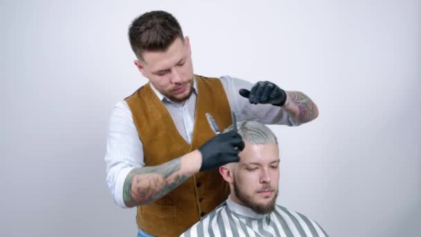 Un jeune homme se fait couper les cheveux avec des ciseaux à cheveux avec un peigne . — Video