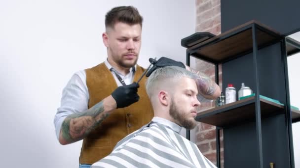 Un joven se corta el pelo con tijeras de pelo con un peine . — Vídeos de Stock