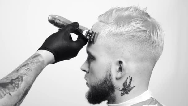 Zbliżenie ostrzyc włosy mężczyzna. Męskie dłonie Fryzjer golenie człowiek z elektryczne maszynki do golenia w fryzjera. Fryzjer z włosów trymer do strzyżenia włosów — Wideo stockowe