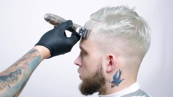 Corte de pelo en barbería con una navaja eléctrica. Retrato de un hombre rubio — Vídeos de Stock