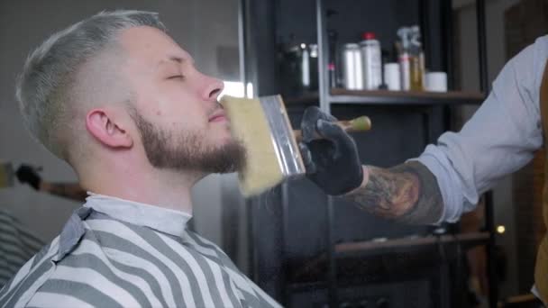 Barbeiro sorve talco em uma escova. O vídeo tem uma tonalidade marrom . — Vídeo de Stock
