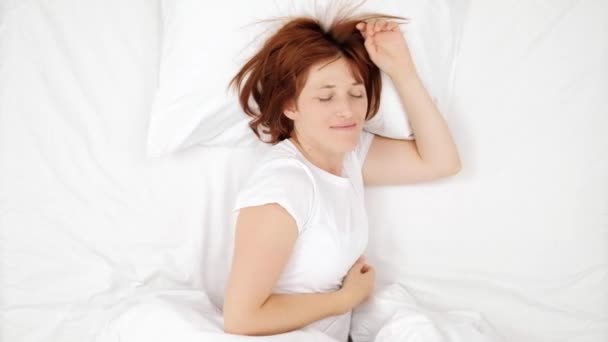 Mulher bonita cabelo vermelho jovem dormindo em uma cama branca. Bom dia. Dawn, subida matinal. A fêmea está a dormir. Menina dormindo e descansando sozinha em sua cama, sonhando. vista de cima . — Vídeo de Stock