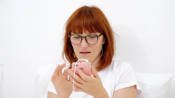 年轻有吸引力的女性看, 并在智能手机, 而短信她的朋友, 使用手机, 白色背景 — 图库视频影像
