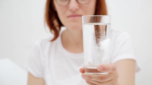 Девушка, держащая стакан воды с лекарством. Белый фон — стоковое видео