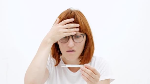 Foto van ongelukkige jonge vrouw bedrijf thermometer in handen, meten van de lichaamstemperatuur terwijl het lijden van influenza. Vrouw van de gefrustreerd met thermometer van het aanraken van haar voorhoofd, ziek gevoel — Stockvideo