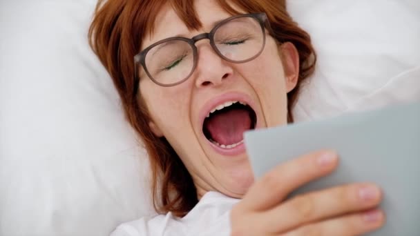 Niña bostezando acostada en la cama con un libro. de cerca — Vídeos de Stock