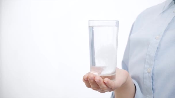 Ragazza che tiene un bicchiere d'acqua con la medicina. Fondo bianco — Video Stock