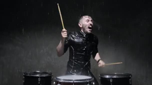 De drummer op de trommel houten stokken en waterdruppels vliegen in alle richtingen. — Stockvideo