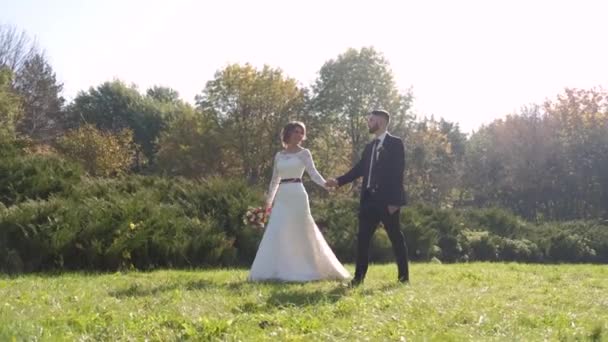 Bruidspaar tijdens een wandeling in het park. Bewegende en emotionele moment. — Stockvideo