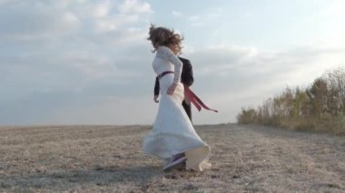 Mutlu genç çift el ele tutuşarak dışarıda eğleniyor bir geniş alan çalıştırın. Kırsal. Çayır üzerinde çalışan kadın ve erkek. Mutlu neşeli aile açık. Güneş parlaması. Yavaş hareket Full Hd 1080 p