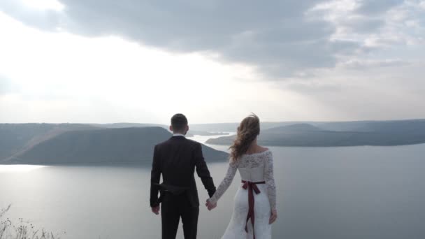 Magical and mystical couple looks at the coast from a cliff. — Stock Video