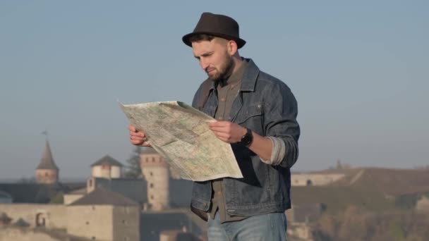 Молодий мандрівник з картою на відкритому повітрі, стародавній фон замку — стокове відео