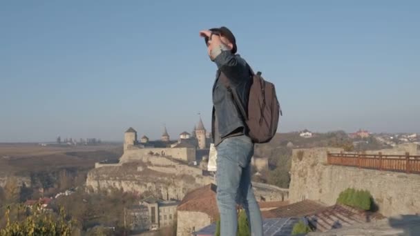 Muž cestovatel s batohem zkoumá město při pohledu na panoramatický výhled na město a pobřeží. Pojem cestovní je objevování nových míst. — Stock video