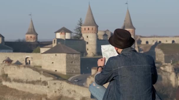 Jeune voyageur homme avec carte en plein air, ancien fond du château — Video