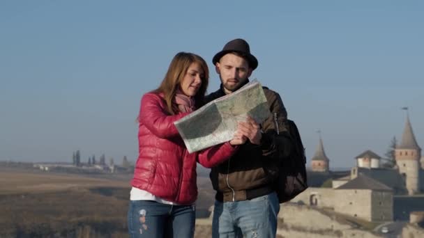 Jonge toeristen die van de lokale kaart op de oude straat achtergrond, bladeren op zoek naar nieuwe bestemming. Buitenshuis. — Stockvideo