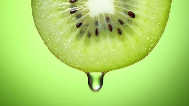 De cerca o macro de una rebanada de kiwi, una gota de agua cae en cámara lenta . — Vídeo de stock