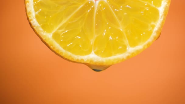 Agua cayendo en una rebanada de naranja, frutas para la dieta y alimentos saludables. Fondo anaranjado — Vídeos de Stock
