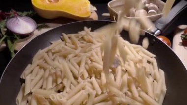 Pişmemiş makarna makarna ile kızartma tavası. Ağır çekimde düşmek