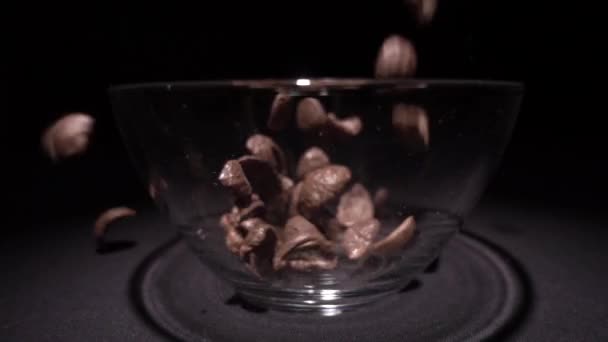 Brown chocolate corn flakes fall in a plate with a pattern of flowers on the edge and are filled with milk. Closeup. Slow mo, slo mo, slow motion, high speed camera, — Stock Video