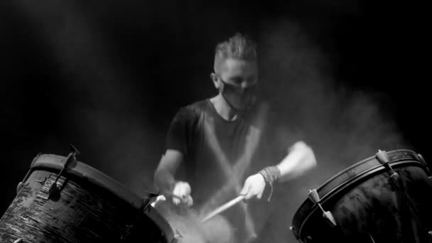 Жестокий человек играет на барабанах на черном фоне — стоковое видео