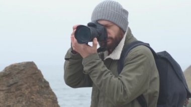 Fırtınalı bir deniz yakalayan sakallı açık hava fotoğrafçısı