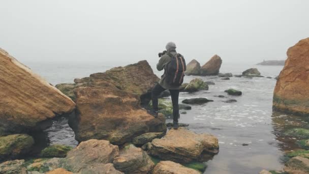 Jovem fotógrafo tirando fotos de penhasco oceânico com câmera DSLR — Vídeo de Stock