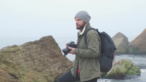 Joven fotógrafo tomando fotos del acantilado del océano con cámara réflex digital — Vídeo de stock