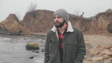 Dalgın adam deniz boyunca yürüyor. O ileriye bakıyor ve kamera, soğuk sonbahar hava