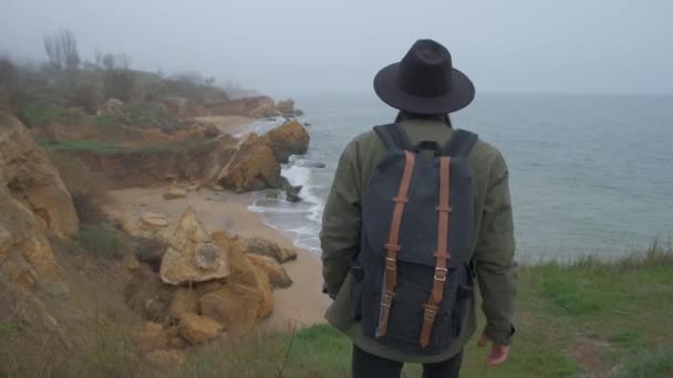 Turista com uma mochila em um passeio na beira de um penhasco — Vídeo de Stock