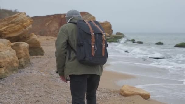 Jeune homme barbu jette des pierres à l'eau le soir . — Video