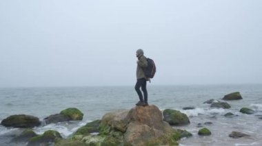 Taş dağları ve sahili olan ıssız bir yerde yalnız bir turist. Sahil ve iyi duygular, hayatın duygusal kavramı. Hipster düşünme ve ufka bakarak