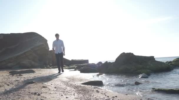 Mann, der bei Sonnenaufgang am Meeresstrand spaziert — Stockvideo