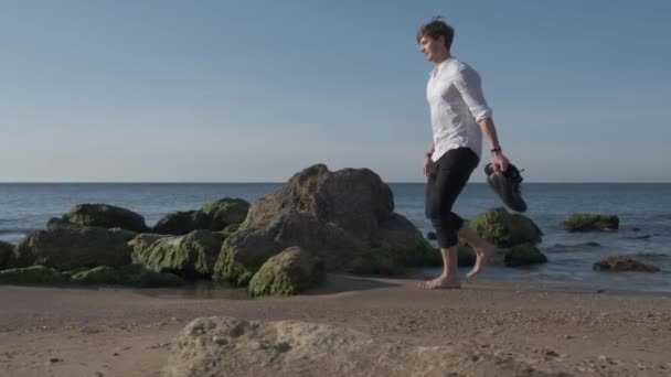 Mann, der bei Sonnenaufgang am Meeresstrand spaziert — Stockvideo