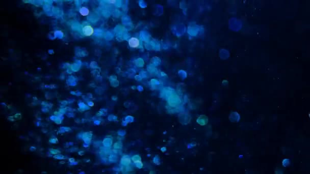 Paillettes bleues dans le flou sur un fond noir . — Video