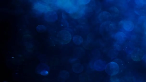 Blue glitter in blur on a black background. — Stock Video