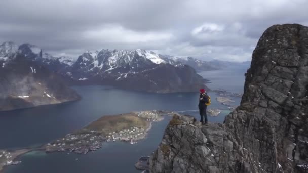 Imágenes aéreas de senderista masculino en la cima de la montaña con vistas a hermosos paisajes de las islas Lofoten en el paisaje, Archipiélago Noruega , — Vídeos de Stock