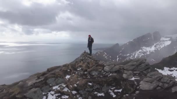 Aerial footage of male hiker on mountain top overlooking beautiful Lofoten Islands scenery in scenic , Archipelago Norway, — Stock Video