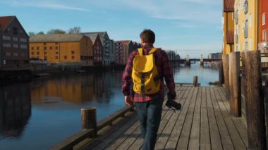 Şehir merkezinde yürürken sarı bir sırt çantası ile çekici genç yakışıklı turist ve bir fotoğraf çekerken, yavaş hareket