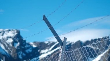 Güzel karlı bir dağ arka planda iken dikenli teller in sabit bir çekim.