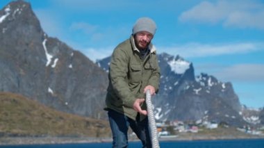 Ciddi denizci bir gemide demirleme sırasında kalın bir ip çeker.