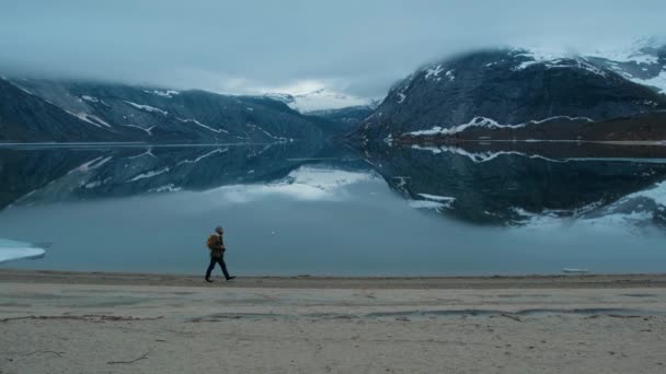 Turista con zaino fare una lunga passeggiata lungo la riva la sera. Vista sulle montagne — Video Stock