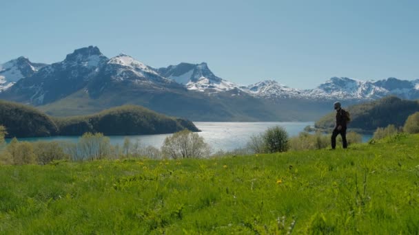 旅行マン見事な山の風景と緑の芝生の丘の上を歩いてノルウェー — ストック動画