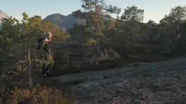 Yürüyüş adam yokuş yukarı yürüyor. Yaz aylarında bir iz üzerinde açık havada yürüyüş erkek turist trekking. Güzel yaz günbatımı. Sırt çantası ile Hiker Man yürüyüş. Hiker adam